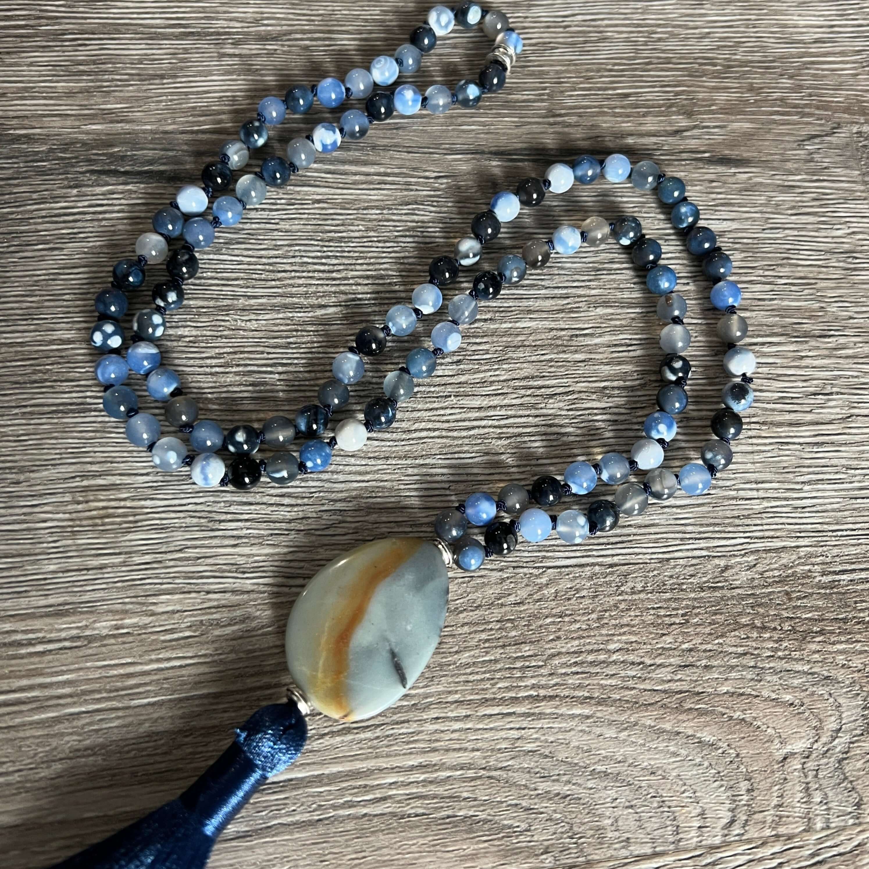 Winter Morning Mala This mala was made with Black-Blue Agate and Amazonite gemstones which provide strength and inspiration to the wearer. Zodiac Signs: Gemini & Virgo. Chakras: Third Eye, Root, Crown, Throat & Heart. Handmade with authentic crystals and