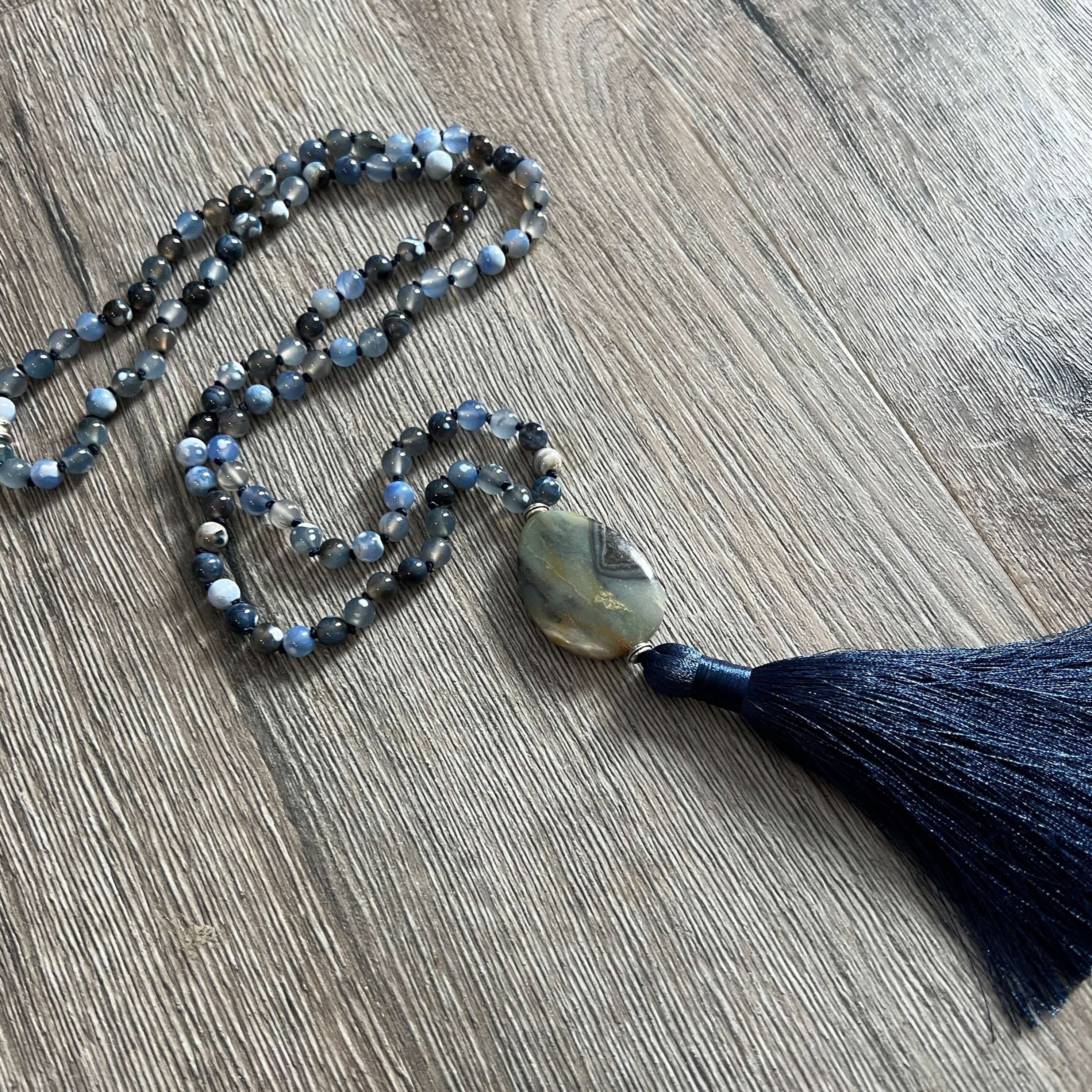 Winter Morning Mala This mala was made with Black-Blue Agate and Amazonite gemstones which provide strength and inspiration to the wearer. Zodiac Signs: Gemini & Virgo. Chakras: Third Eye, Root, Crown, Throat & Heart. Handmade with authentic crystals and
